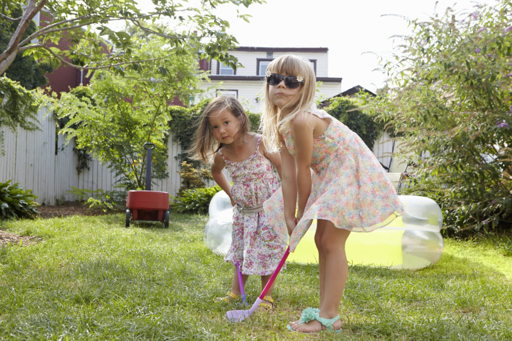 Girls playing kids golf in garden